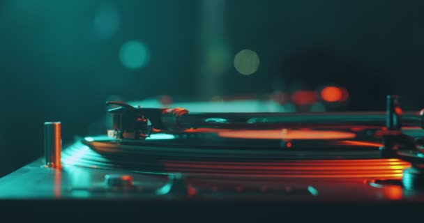 Вініловий музичний запис, що обертається на DJ turntable у барвистому світлі, крупним планом. Концепція вечірки та музики — стокове відео