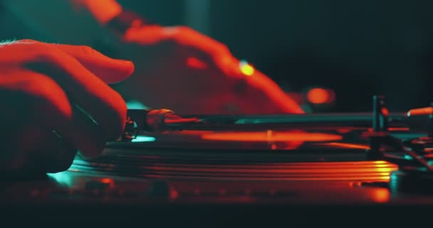 Deejay grający muzykę, wkładający igłę na płytę winylową wirującą na gramofonie DJ podczas imprezy, zbliżenie — Wideo stockowe