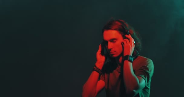 Dansen stijlvolle jonge man in hoofdtelefoon luisteren naar muziek genieten in rood studio licht, kopiëren ruimte. — Stockvideo