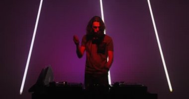 DJ 'lik yapan havalı adam DJ konsolunda müzik çalıyor ve gece kulübünde dans ediyor. Modern müzik çılgınlığı.