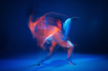Renkli neon renkli stüdyo ışığı altında dans eden melez genç kız. Uzun pozlama. Çağdaş hip hop dansı