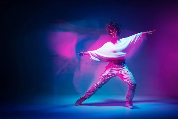 Mieszana rasa żeńska tańcząca w kolorowym neonowym świetle. Studio zdjęcie z długą ekspozycją. Wyraźny współczesny hip hop dance — Zdjęcie stockowe