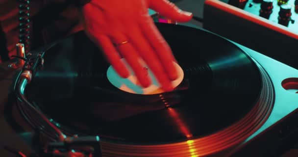 DJ spinning, scratching vinyls in night club during rave. Hands of dj rotate vinyl record on turntable, close-up — Stock Video