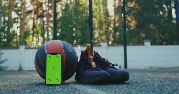 Maqueta de teléfono de pantalla verde con marcadores de seguimiento, pelota de baloncesto, zapatos deportivos. Smartphone Chroma key — Vídeo de stock