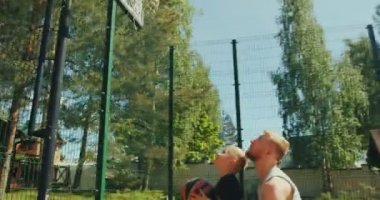 Basketbolcular aile babasını ve oğlunu basketbol sahasında spor yapar. Babası çocuğa pota toplamada yardım ediyor. Ellerinde çocuk büyütüyor.