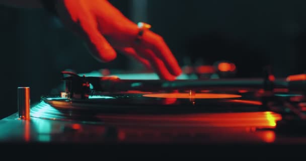 Deejay grający muzykę, wkładający igłę na płytę winylową wirującą na gramofonie DJ podczas imprezy, zbliżenie — Wideo stockowe
