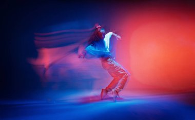 Renkli neon renkli stüdyo ışığı altında parmak uçlarında dans eden kadın. Uzun pozlama. Çağdaş hip hop dansı