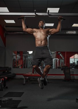 Kas yığını Afrikalı Amerikalı adam barfiks çekiyor ya da spor salonunda antrenman yapıyor.