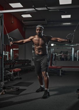 Yakışıklı, kaslı, atletik, Afrika kökenli Amerikalı erkek. Göğüs kası egzersizi yapıyor. Spor salonunda göğüs kaslarını çalıştırıyor.