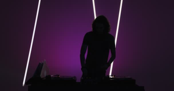 Silhouette von coolen modernen männlichen DJs, die Schallplatten an der DJ-Konsole in einem Nachtclub spielen. Nachtleben und Party — Stockvideo