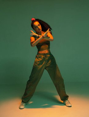 Stüdyo ışığında dans eden melez bir genç kız. Kadın rap şarkıcısı etkileyici hip hop dansı gösterisi