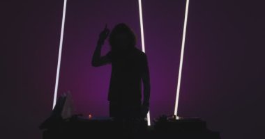 Dans eden modern erkek DJ 'in silueti gece kulübündeki DJ konsolunda vinil çalıyor. Gece hayatı ve parti.