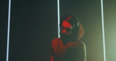 Havalı DJ, uzun saçlı, kulaklıklı genç adam DJ 'de müzik dinliyor ve dans ediyor. Gece hayatı partisi