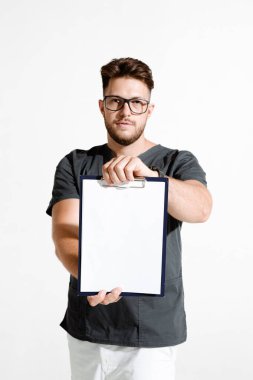 Erkek doktor, klinik reklamları için boş bir sayfa gösteriyor. Beyaz arkaplanda stüdyo resmi