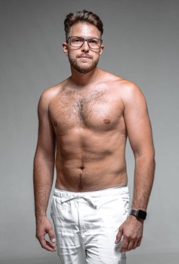 Young 30s male in glasses with naked torso. Overeating, fatness, overweight, physical inactivity and slimming concept clipart