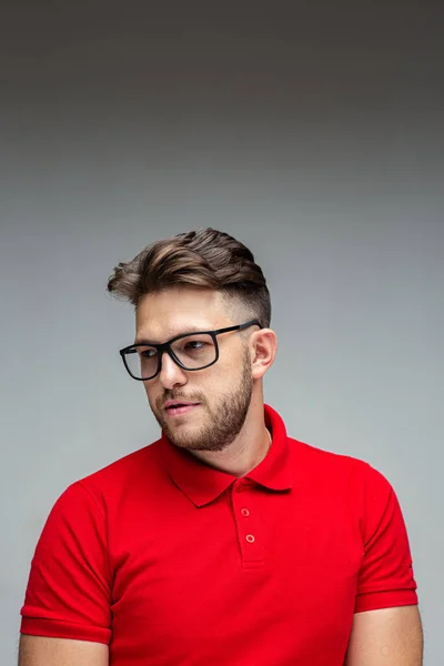 Sério bem sucedido jovem homem de negócios em óculos com corte de cabelo elegante, retrato de estúdio em fundo cinza — Fotografia de Stock