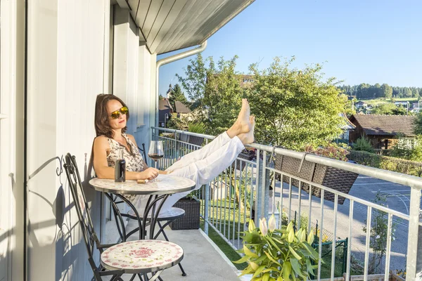 Niedliche Frau trinkt Wein auf einer Terrasse Stockbild