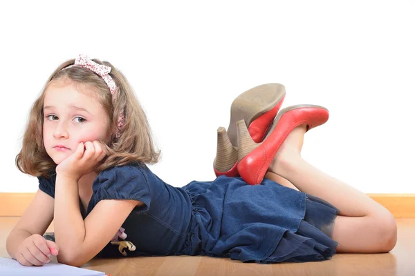 Mädchen in den Schuhen der Mutter liest und posiert — Stockfoto