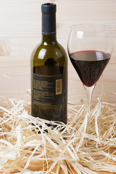 Botella y copa de vino tinto en paja —  Fotos de Stock