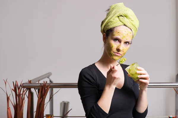 Giovane donna con una maschera facciale avocado — Foto Stock