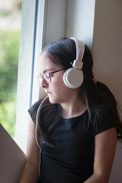 Милая девушка в очках слушает музыку — стоковое фото