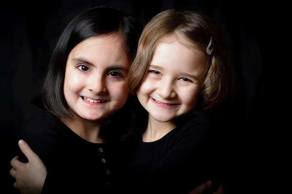 Two little girls posing on a black background — Stock Photo, Image