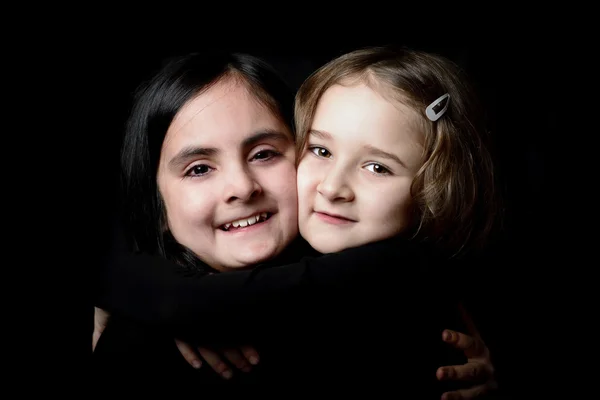 Two little girls posing on a black background — Stock Photo, Image