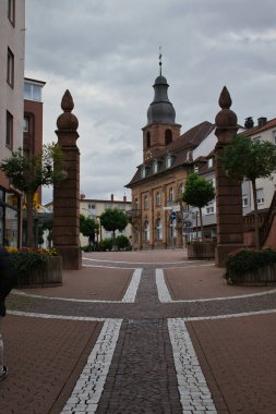 Hauptstrasse 'deki sütunlar, Pirmansens, Almanya' nın ana caddesi. Lüteriyen 'de bir binanın arkasında kulesi var..