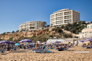 Malta 'da sıcak bir sonbahar gününde, üzerinde bir uçurum olan Golden Bay plajındaki insanlar..