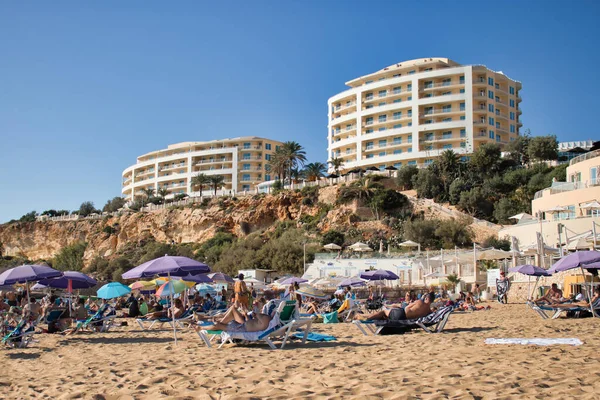 Malta 'da sıcak bir sonbahar gününde, üzerinde bir uçurum olan Golden Bay plajındaki insanlar..