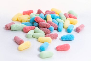 Kırmızı, mavi, sarı ve yeşil ekşi şekerler beyaz arka planda bir yığın içinde.