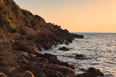 Gün batımında, Malta 'daki Golden Bay' de kayaların üzerinde turuncu gökyüzü..
