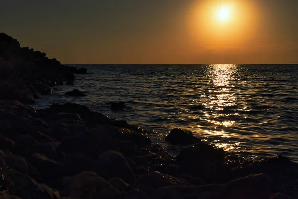 Orange sunset over the ocean at Golden Bay in Malta.