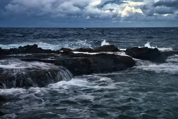 マルタのカワラのビーチで暗い嵐と曇りの日に海の岩の上を走る水 — ストック写真