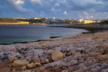Gün batımında Malta, Qawra 'da deniz kıyısındaki binalara ışık vuruyor..