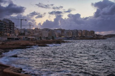 St. Paul 's Bay, Malta' da bir sonbahar gecesinde binalar ve ışıklar olan kıyı şeridi.
