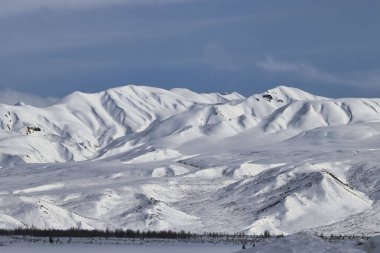 Güneşli bir bahar gününde, Alaska 'daki Denali Otoyolu' nda, yumuşak karların üzerinde parlayan güneş..