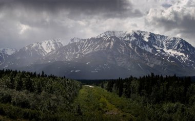 Alaska 'da bir bahar günü Denali Otoyolu' nda dağların üzerinden kara bulutlar..