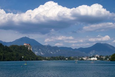 Bled, Slovenya - 30 Temmuz 2021: Slovenya 'da güneşli bir yaz gününde arka plandaki bir tepede Bled Castle ile Gölü' ndeki insanlar.