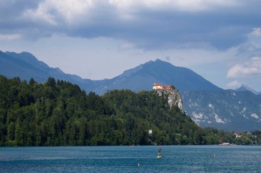 Bled, Slovenya - 30 Temmuz 2021: Slovenya 'da bir yaz günü arka plandaki bir tepede Bled Castle ile Gölü' ndeki İnsanlar.