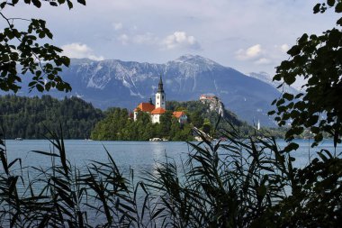 Bled, Slovenya - 30 Temmuz 2021: Slovenya 'da güneşli bir yaz gününde Bled Island' daki Mount Qinw Gölü üzerindeki Meryem Ana Kilisesi.