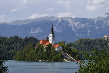 Bled, Slovenya - 30 Temmuz 2021: Slovenya 'da bir yaz gününde Meryem Ana Kilisesi' nin arkasındaki dağlar.