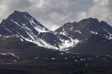 Alaska 'daki Denali Otoyolu' nda bir bahar günü kara bulutların arasından ışık parlıyor.. 