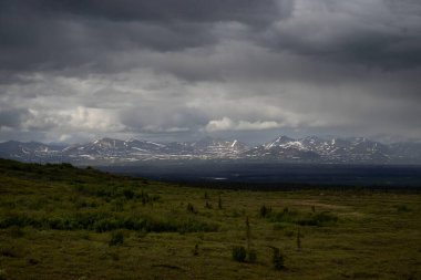 Alaska 'daki Denali Otobanı' nda bir bahar günü bulutların arasından parlayan güneş..