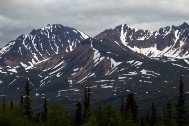 Alaska 'da karanlık ve bulutlu bir yaz akşamında Denali Otoyolu' nun yanındaki karlı dağlarda.. 