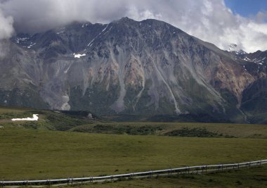Alaska Boru Hattı dağın altında bulutlu bir yaz gününde Alaska 'nın iç kesimlerinde.