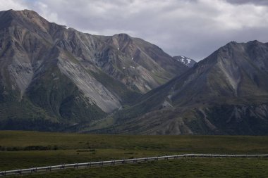 Alaska 'daki Richardson Karayolu yakınlarındaki bir yaz gününde boru hattının üzerindeki dağların üzerindeki bulutlar..