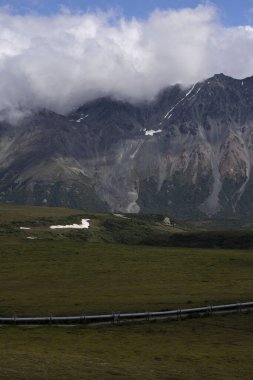 Alaska 'daki Richardson Otoyolu yakınlarındaki bir yaz gününde dağların üzerinden beyaz bulutlar..