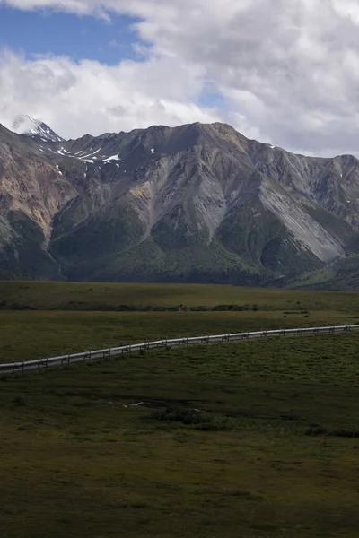 Alaska 'daki Richardson Karayolu yakınlarındaki bir yaz gününde boru hattının üzerindeki dağların üzerinden beyaz bulutlar..