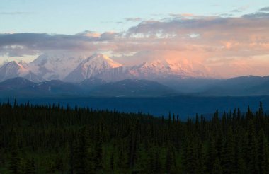 Delta Kavşağı yakınlarındaki karlı dağlarda parlayan pembe ışık, yaz gecesinde Alaska 'da.